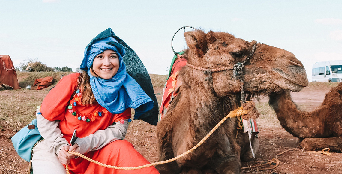 women sitting beside a camel in the dessert