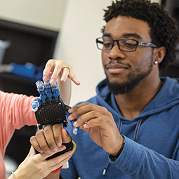 student engaged in experiential learning working with robotic hand 