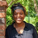 Moeshia is pictured from the shoulders up. She has dark brown skin and is smiling.