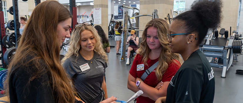Recreation Services Assistants having a brief meeting on the weight floor.