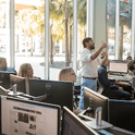 man in white shirt and pants teaches in a computer lab