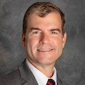headshot of man in gray jacket and garnet and black tie