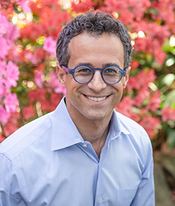 Portrait photo of Berns posing outside in a red flannel shirt and glasses.