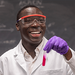 student with goggles on in a chemistry lab working on equipment