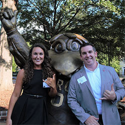 Tara Parker and Blake Edmunds Tara Parker and Blake Edmunds stand with the bronze statue of Cocky giving the spurs up hand signal